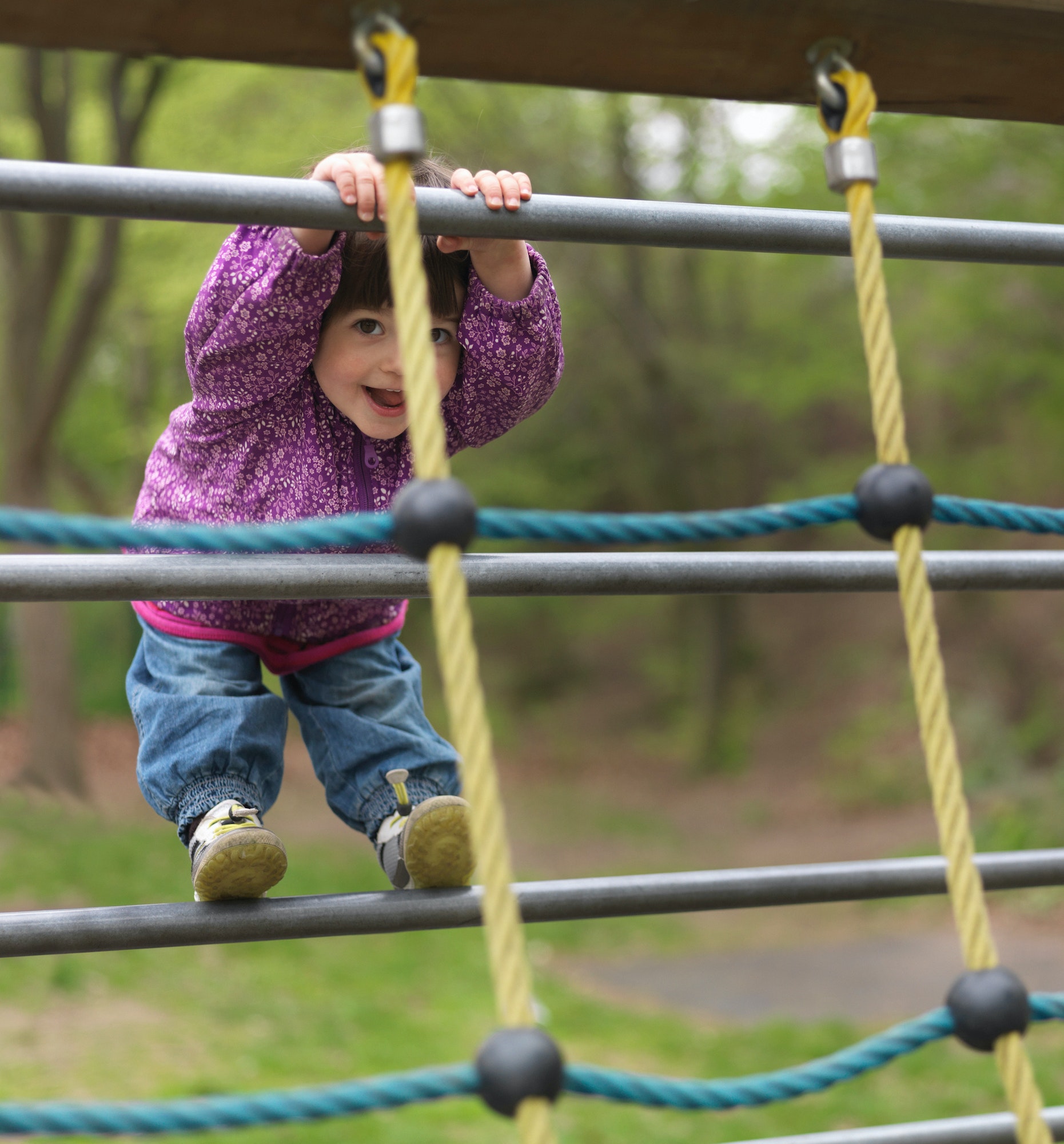 Young girl on climbing frame in playground, portrait